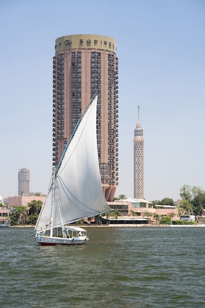 Un velero en el agua, con un edificio alto al fondo.