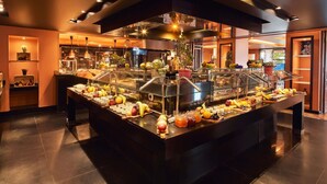 A buffet with a variety of fruits and beverages, a glass display case, and a modern interior design.