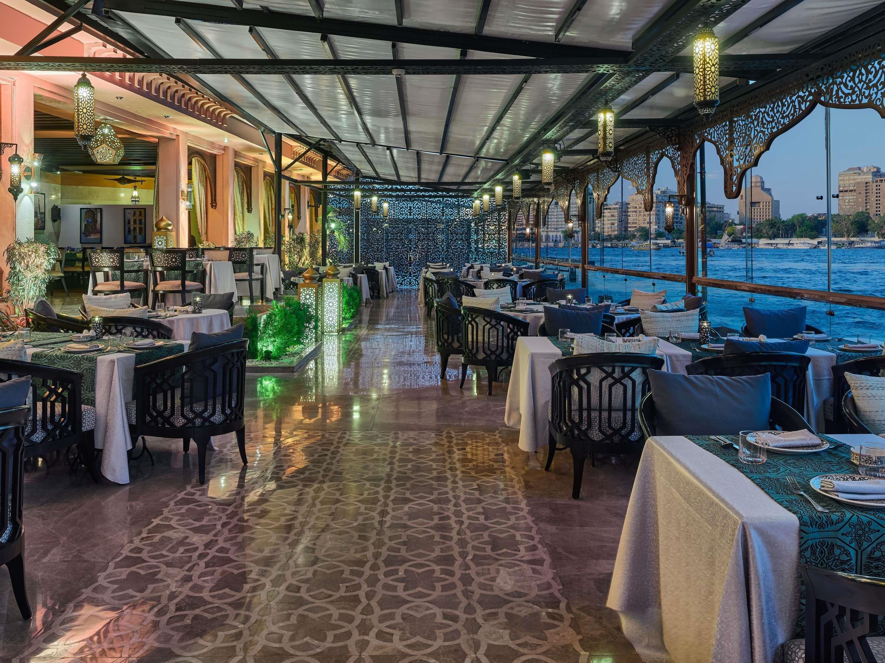 Een restaurant met gedekte tafels, een vloer met patroon en uitzicht op het water.