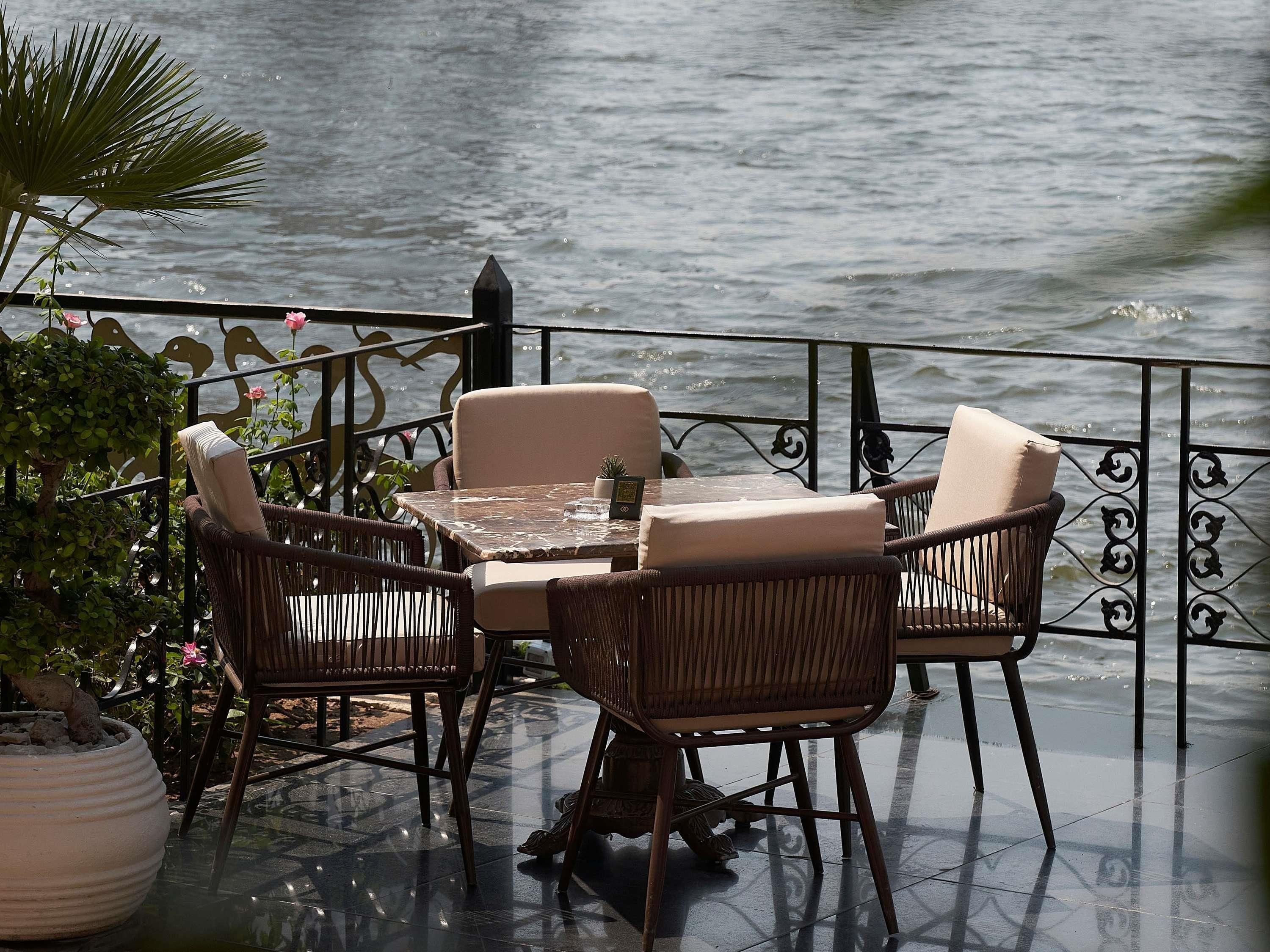 Un'area esterna con posti a sedere, un tavolo, sedie, un parapetto e vista sull'acqua.
