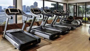 Ein Fitnessraum mit mehreren Laufbändern, einem Rudergerät und einem grünen Trainingsball.