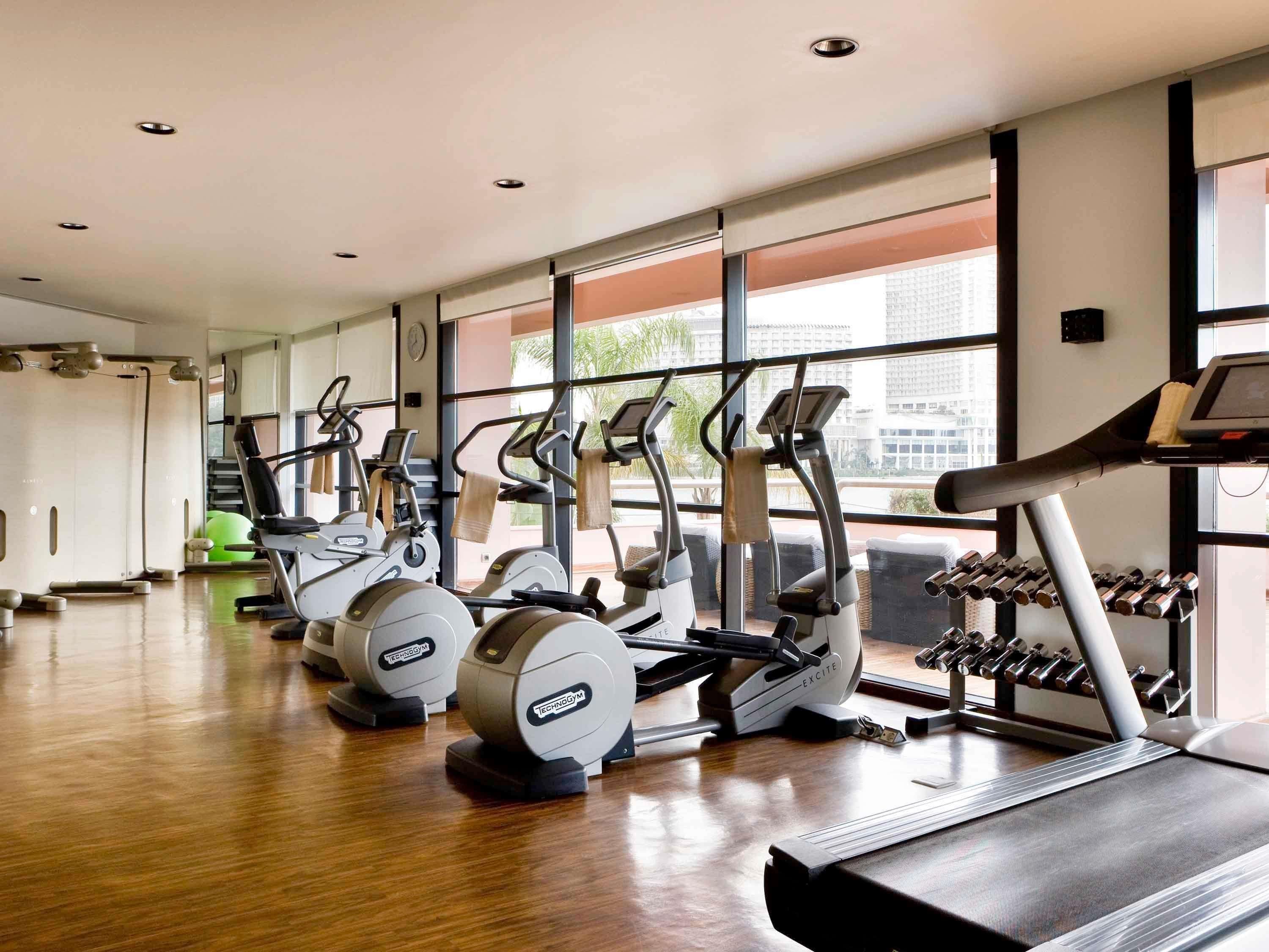 A gym with cardio machines, dumbbells, and a treadmill.
