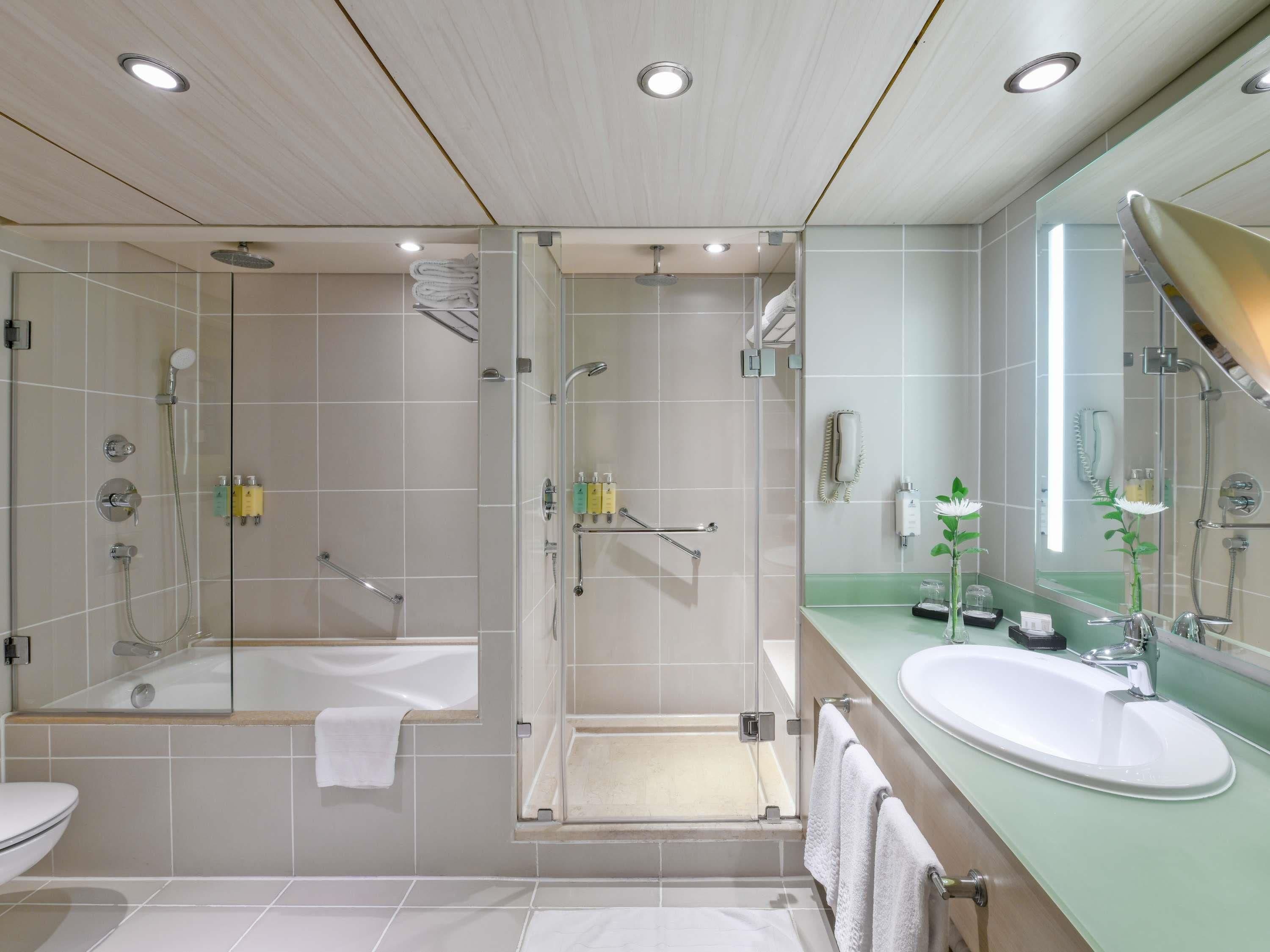 A modern bathroom with a glass-enclosed shower, a bathtub, and a sink with a mirror.