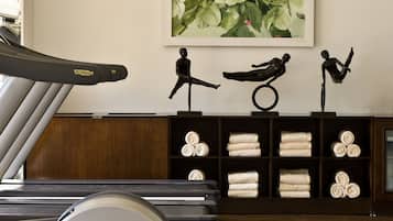 A gym with a treadmill, stationary bikes, and a wall-mounted painting of flowers.