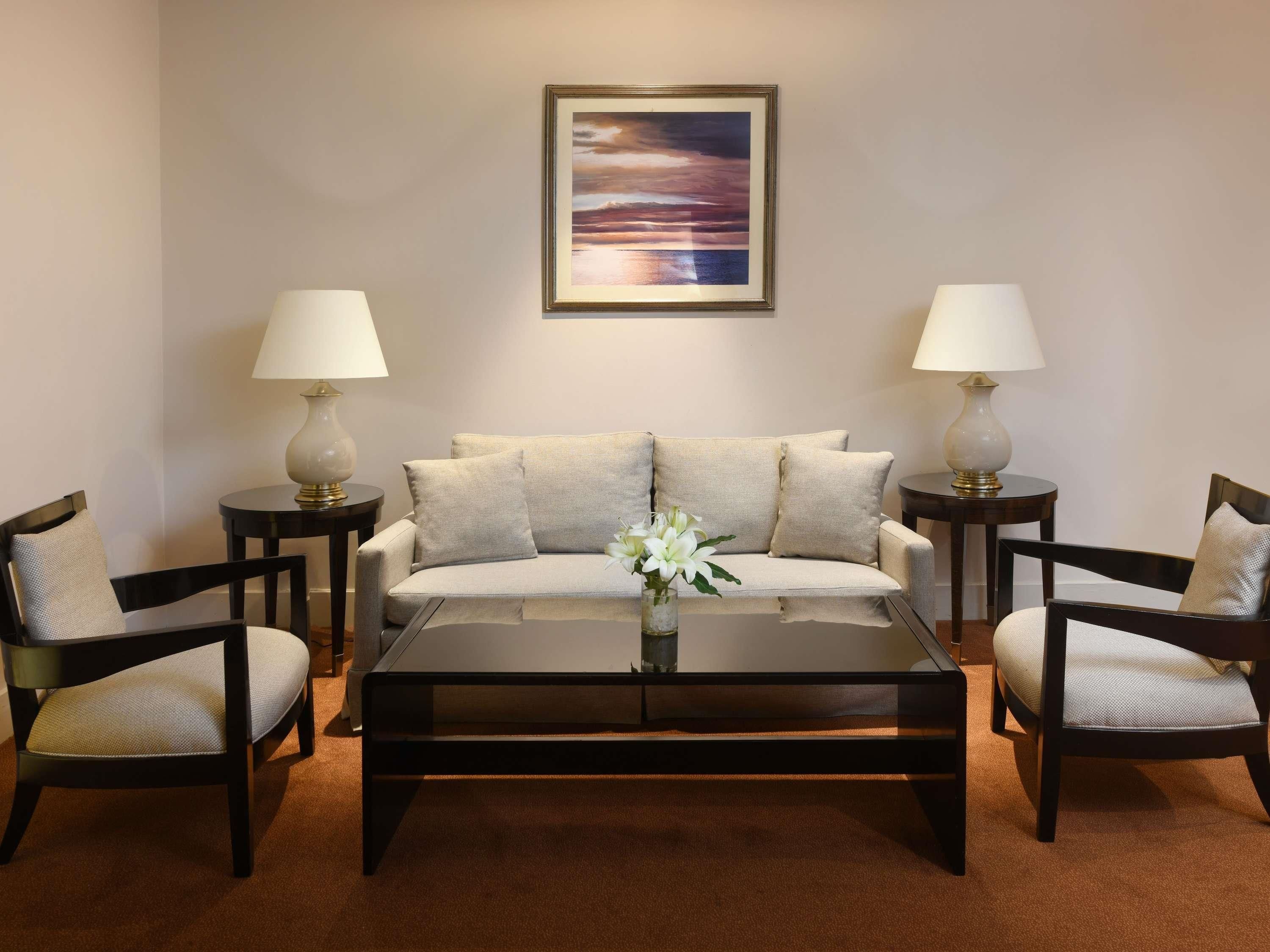 Ein Wohnzimmer mit einer Couch, zwei Sesseln, einem Couchtisch und zwei Beistelltischen mit Lampen.