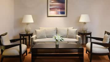 Ein Wohnzimmer mit einer Couch, zwei Sesseln, einem Couchtisch und zwei Beistelltischen mit Lampen.
