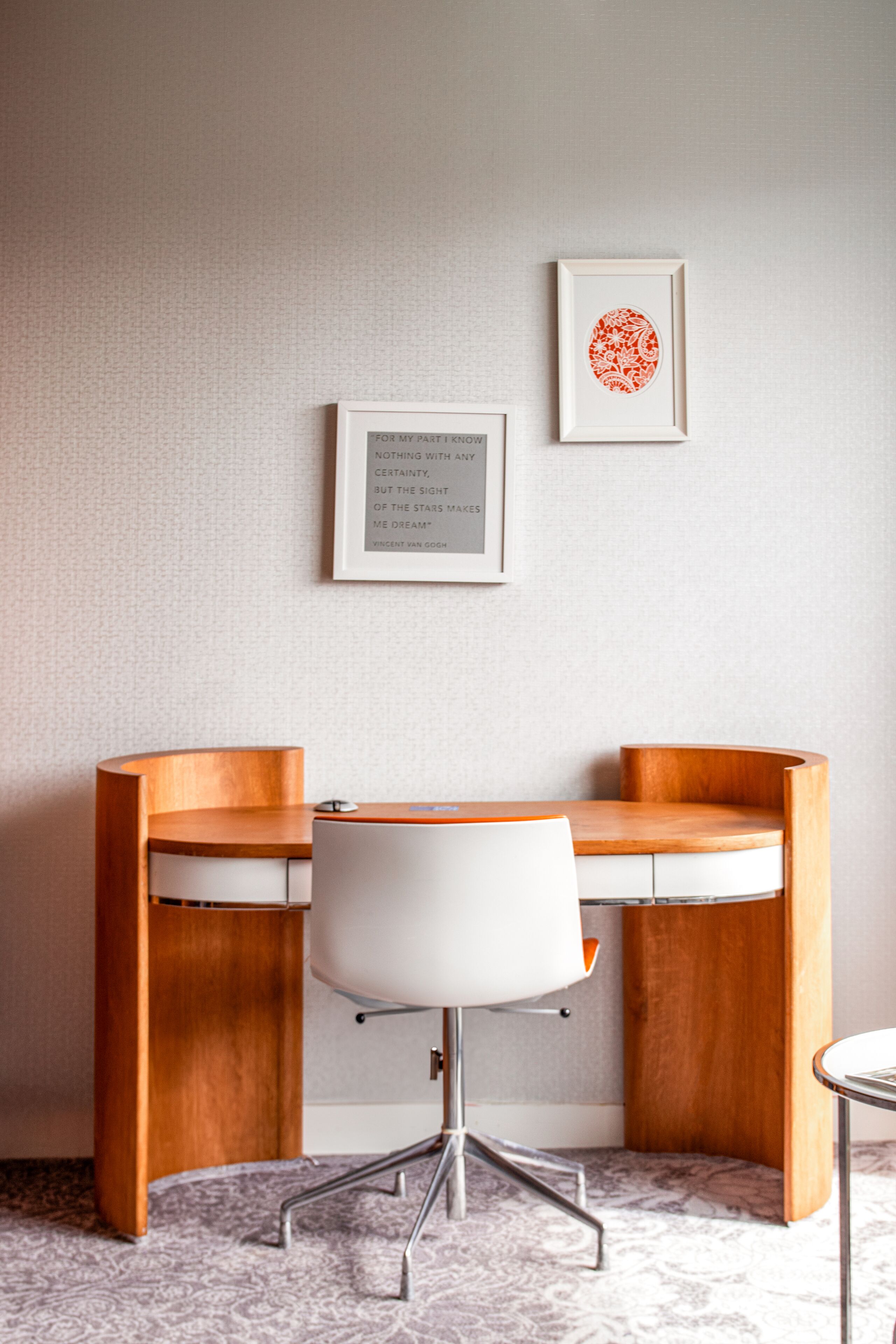 A corner office with a white desk, two wooden chairs, and a framed quote on the wall.