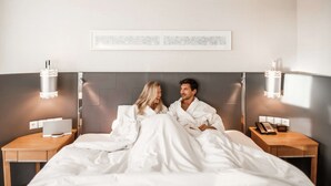 A modern hotel room with a large bed, bedside tables, and wall-mounted lamps.