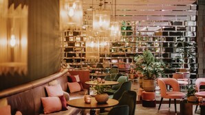 A modern interior with a seating area, tables, and a large bookshelf. - Hilton Rotterdam (Rotterdam)
