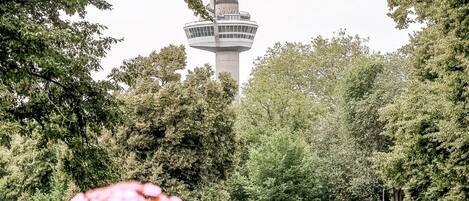 A control tower surrounded by trees and a grassy area with parked cars.