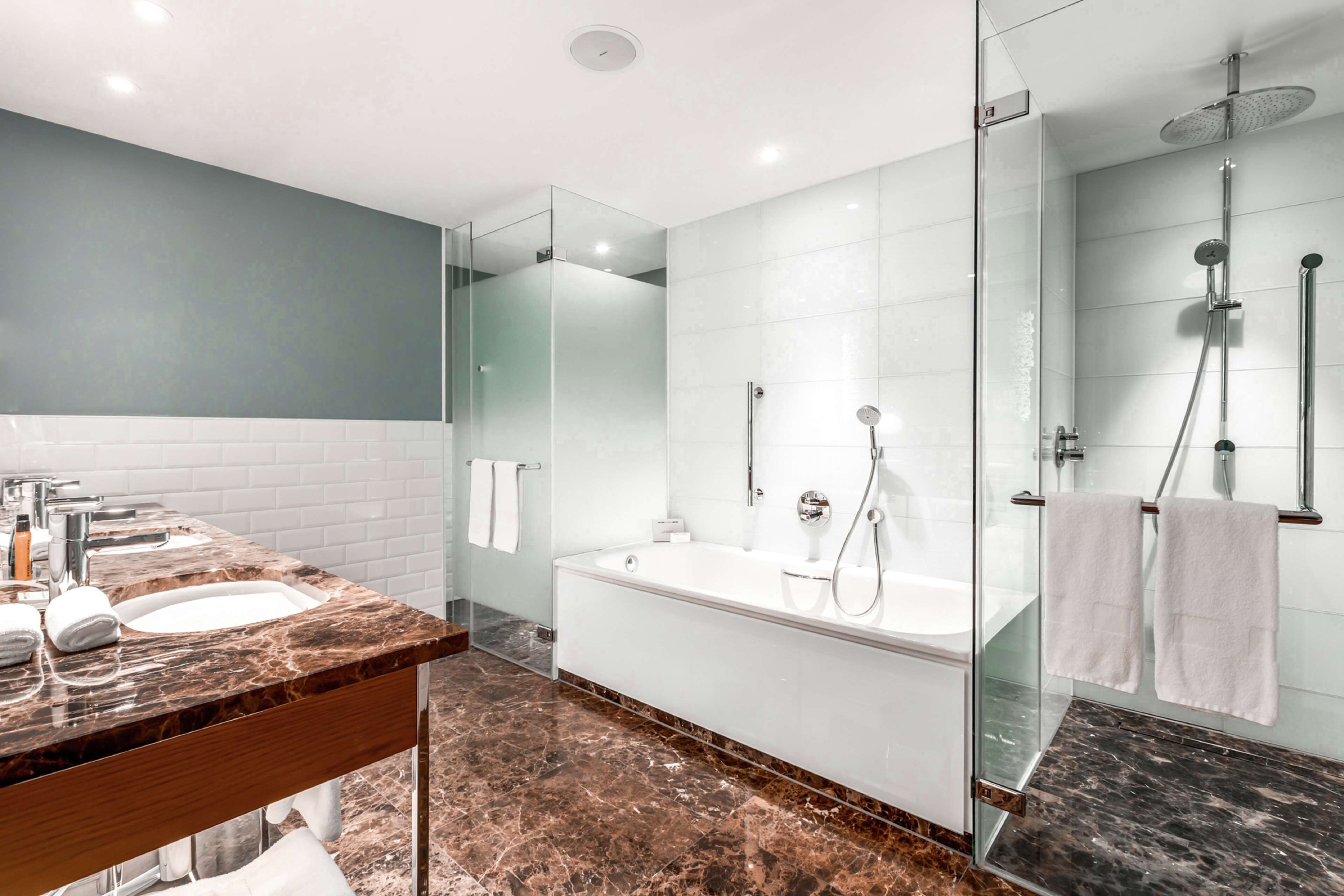 Un baño moderno con tocador de doble lavabo, bañera independiente y cabina de ducha con mampara de vidrio.