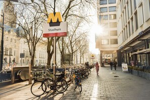 A city street with a bike parking area, a sign for 'Stadhuis', and a tram line.