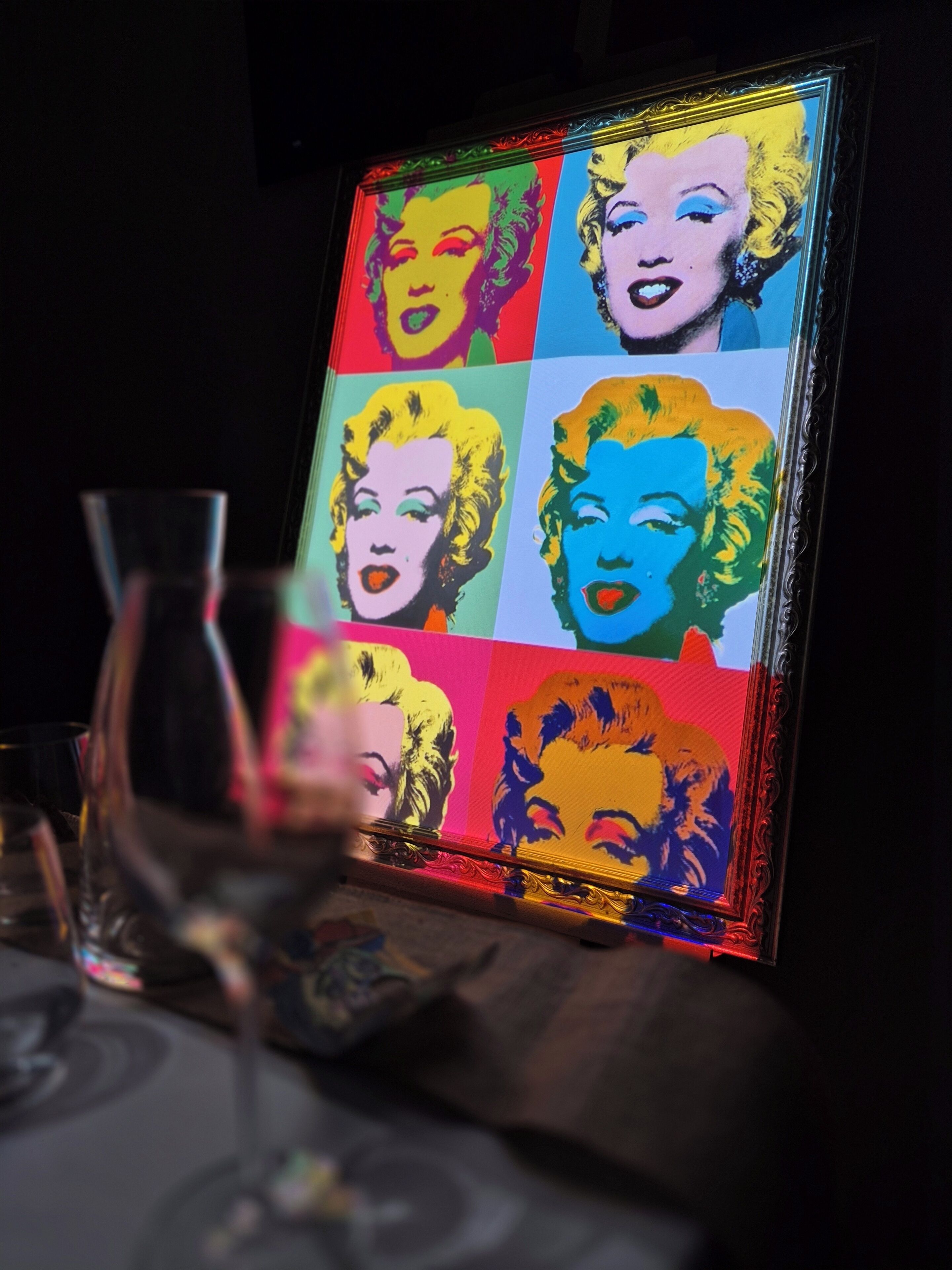 A framed pop art piece with a grid of colorful portraits.