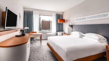 A hotel room with a bed, desk, chair, and a television.