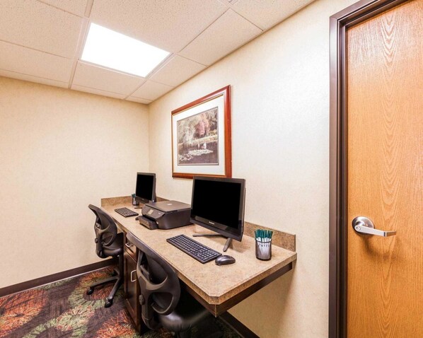 Un bureau d’hôtel équipé de deux écrans d’ordinateur, d’une imprimante, d’un clavier et d’un tableau encadré accroché au mur.