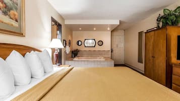 A hotel room with a large bed, a sitting area with a lamp, a bathtub, and a wardrobe.
