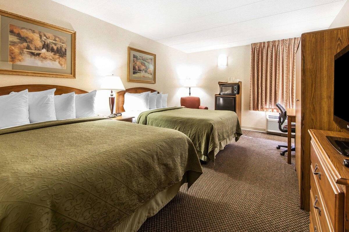 Une chambre d’hôtel avec deux lits, une télévision, un bureau et une chaise.