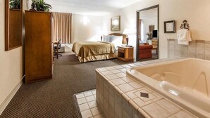 A hotel room with a large bathtub, a bed, a desk with a chair, a wardrobe, and a mirror. - Quality Inn Chillicothe (Chillicothe)