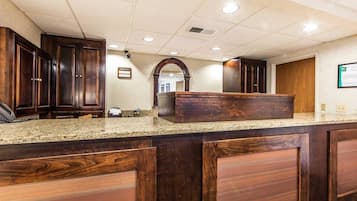 A reception area with a marble counter, wooden cabinets, and a large mirror.