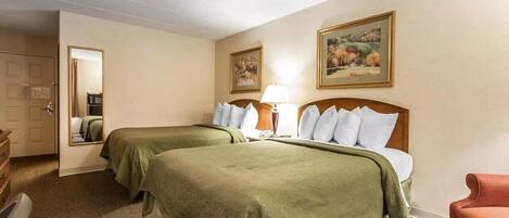 Een hotelkamer met twee bedden, een bureau, een stoel, een lamp en een schilderij aan de muur.