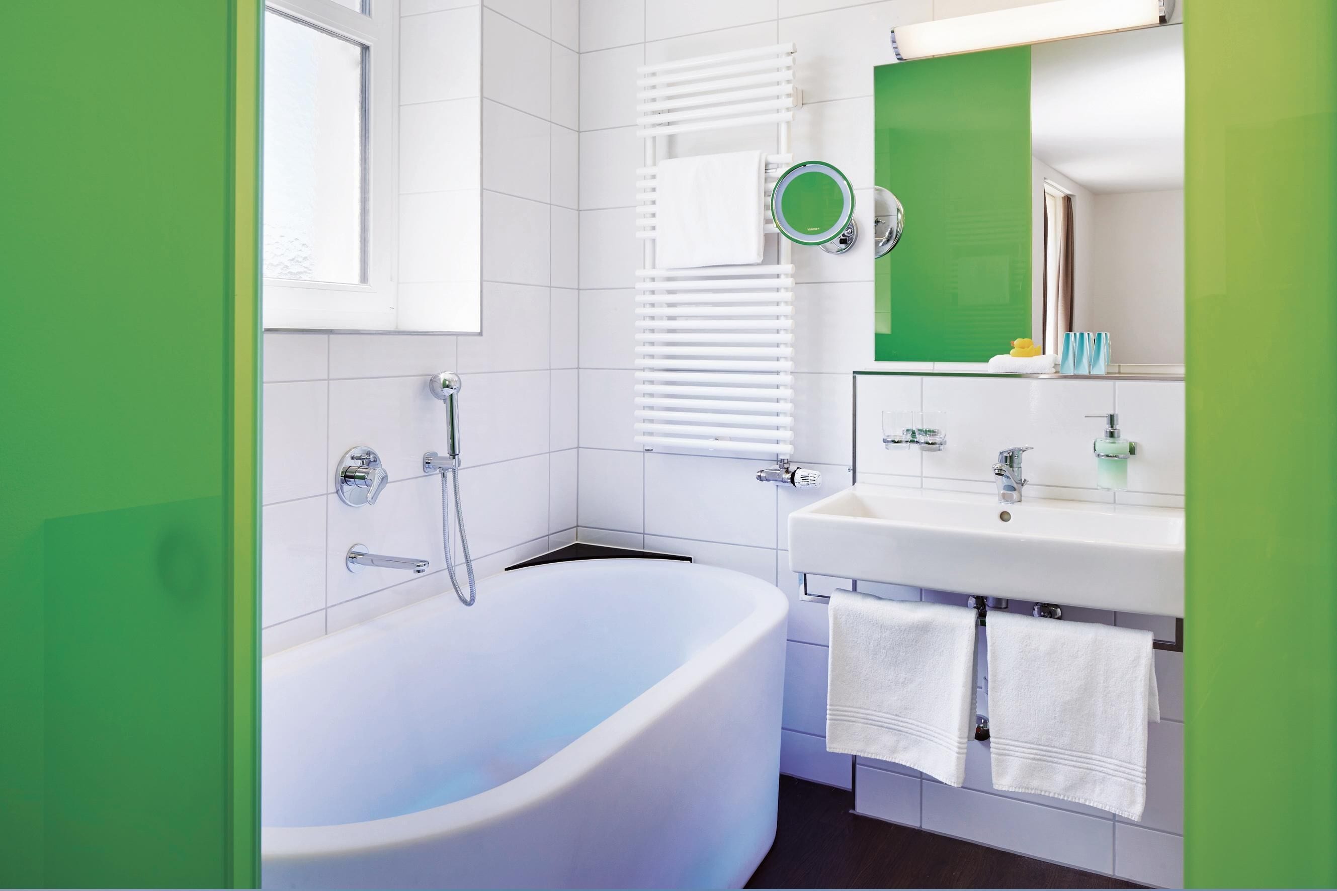 A modern bathroom with a freestanding bathtub, a sink with a mirror, and a window with blinds.