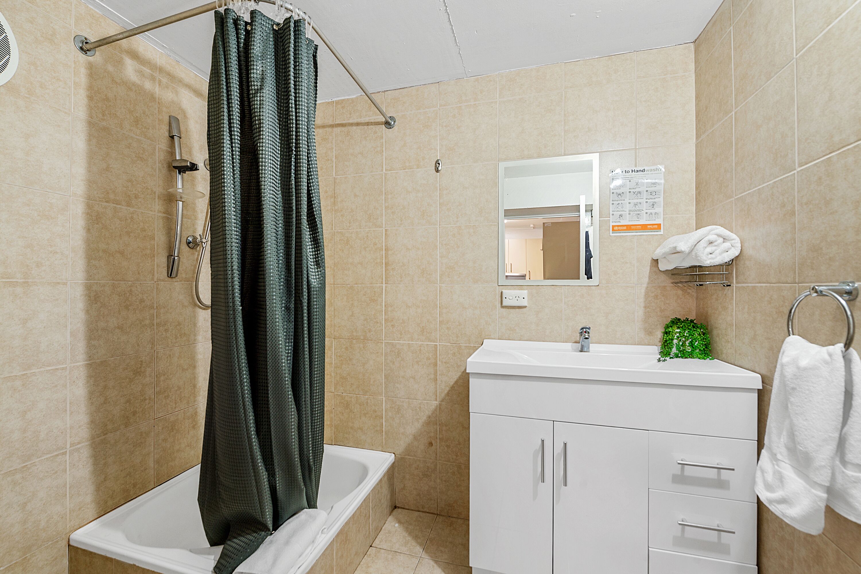 A bathroom with a shower, a sink, a mirror, and a towel rack.