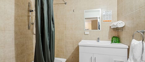 A bathroom with a shower, a sink, a mirror, and a towel rack.