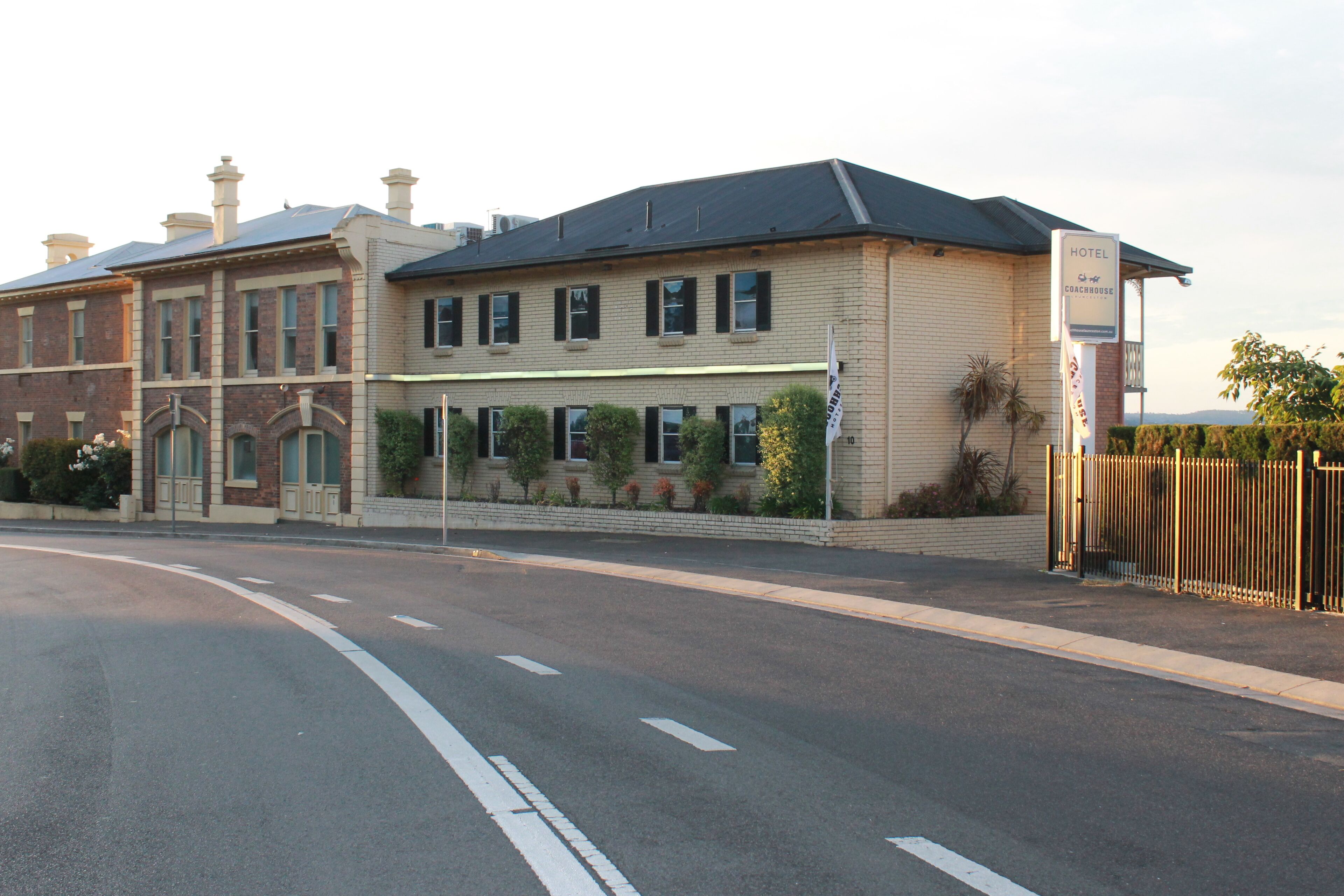 A hotel with a brick facade, multiple windows, and a sign indicating it is a coachhouse.