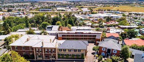 A town with a mix of residential and commercial buildings, including a prominent red brick building with a flat roof and a large sign.