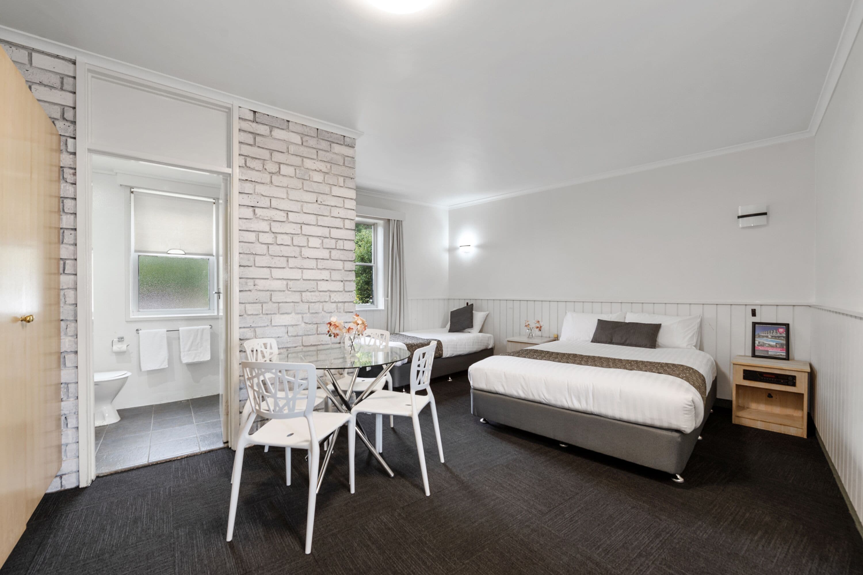 A modern bedroom with a bed, bedside table, and a small window.
