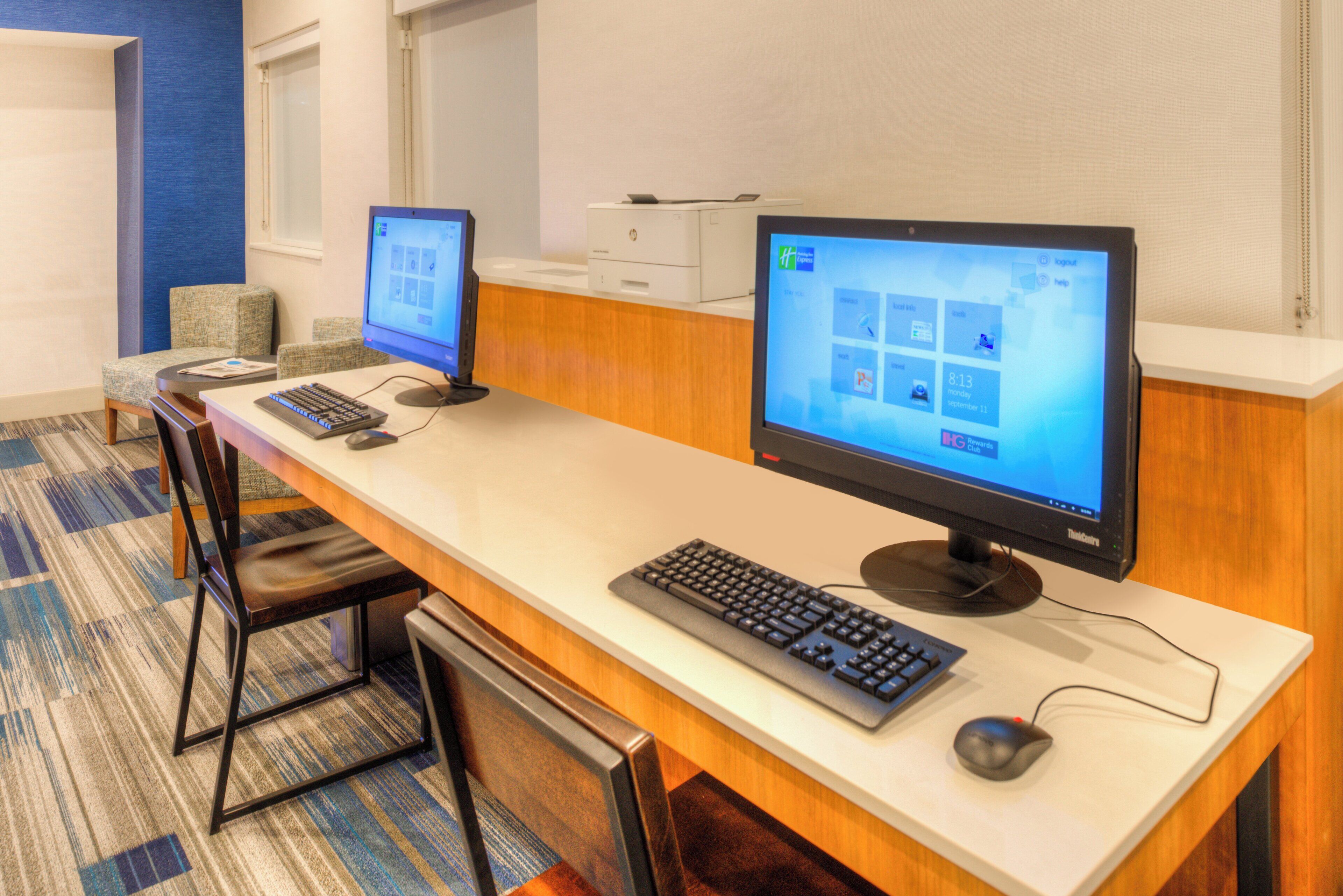 A hotel reception desk with two computer monitors, a keyboard, and a mouse.