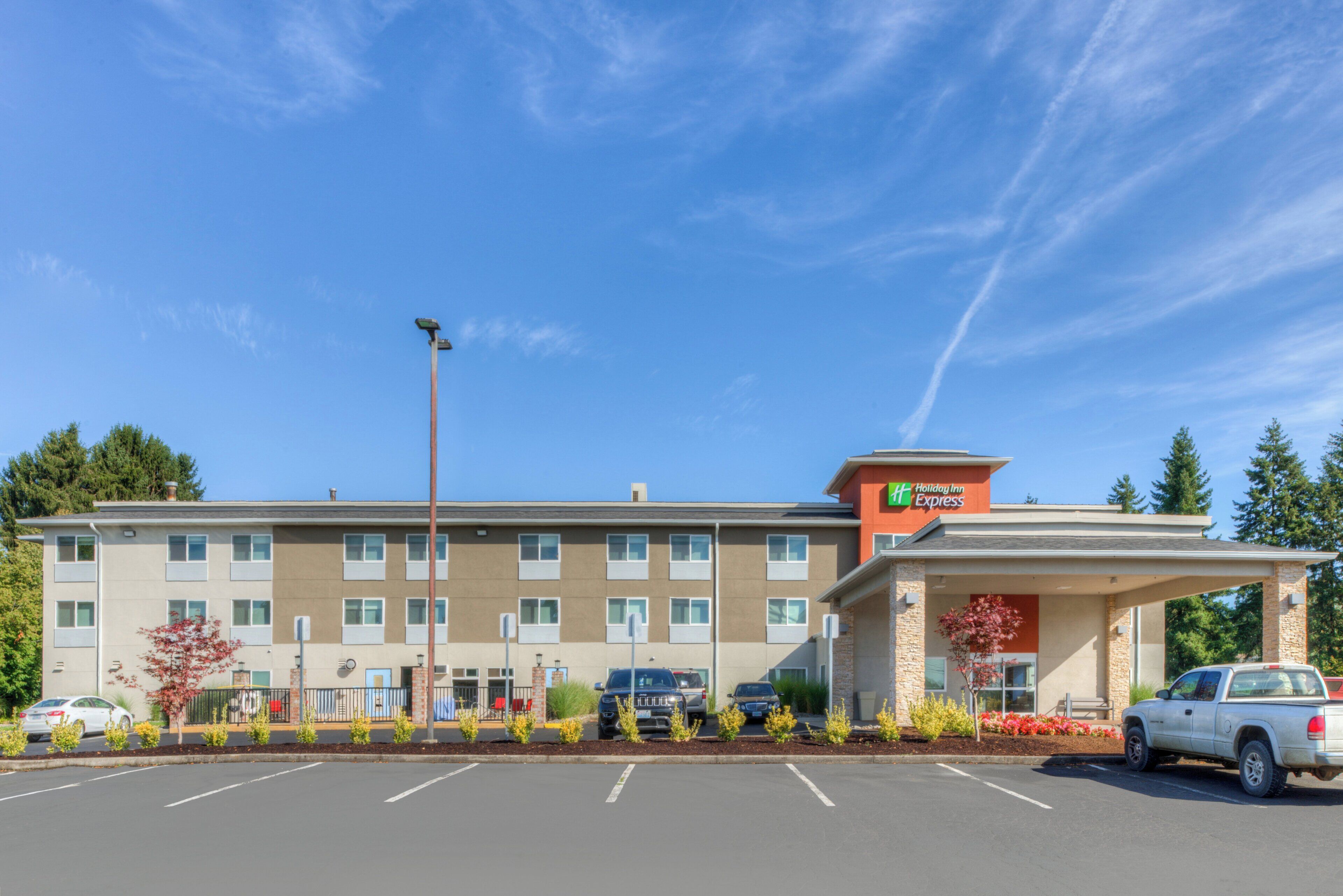 A multi-story hotel with a parking lot, a covered entrance, and a sign for 'Holiday Inn Express.'