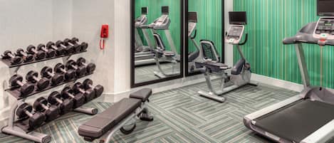 A gym with treadmills, a stationary bike, and dumbbells.