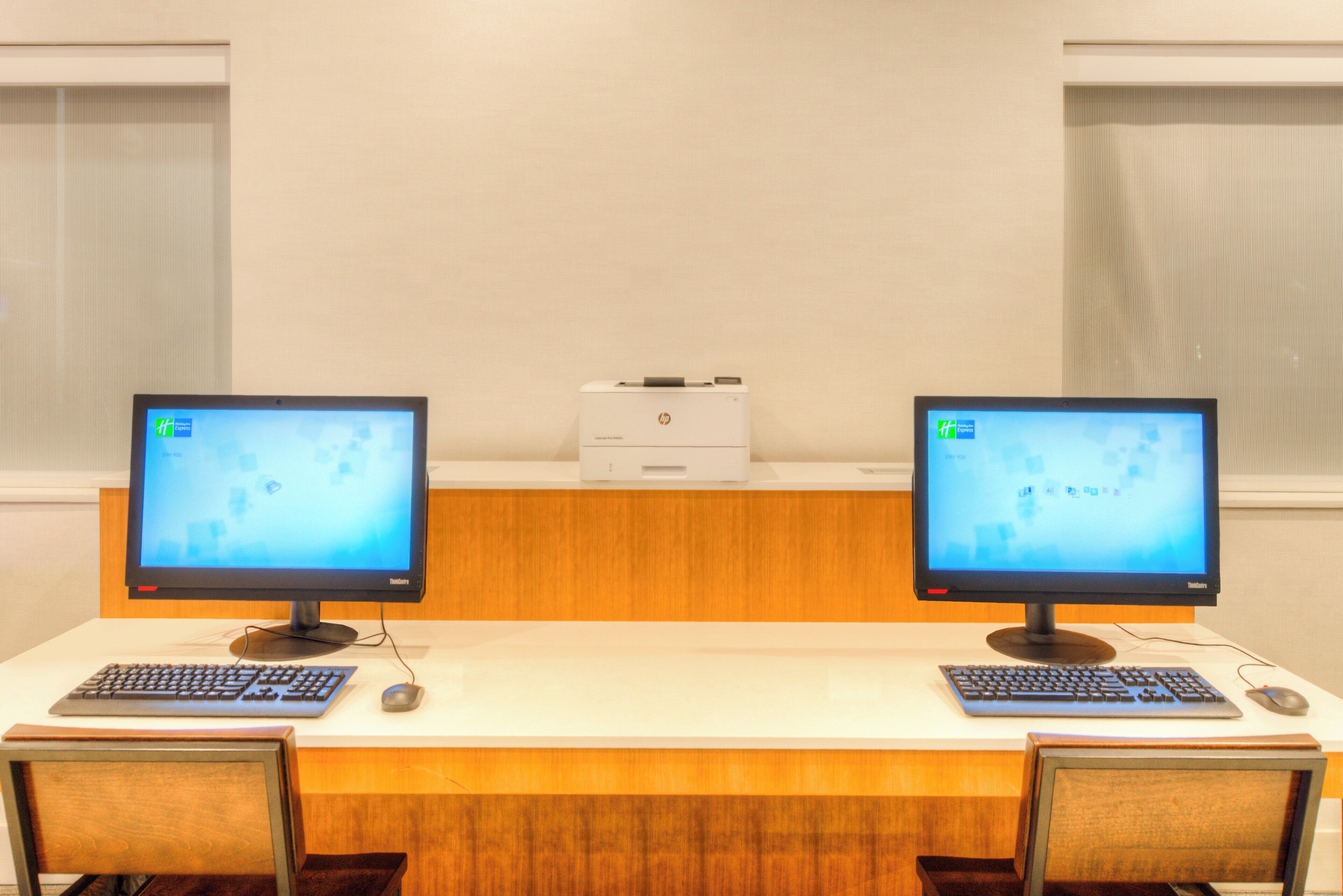 A room with two desks, each with a computer monitor, keyboard, and mouse.