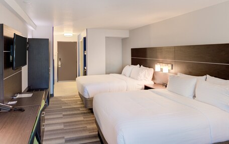 A hotel room with two beds, a desk, and a TV.