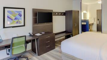 Ein Hotelzimmer mit Bett, Schreibtisch, Stuhl, Fernseher, Kleiderschrank und Bad.