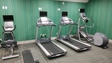 Un gimnasio con cintas de correr, elíptica y bicicleta estática.