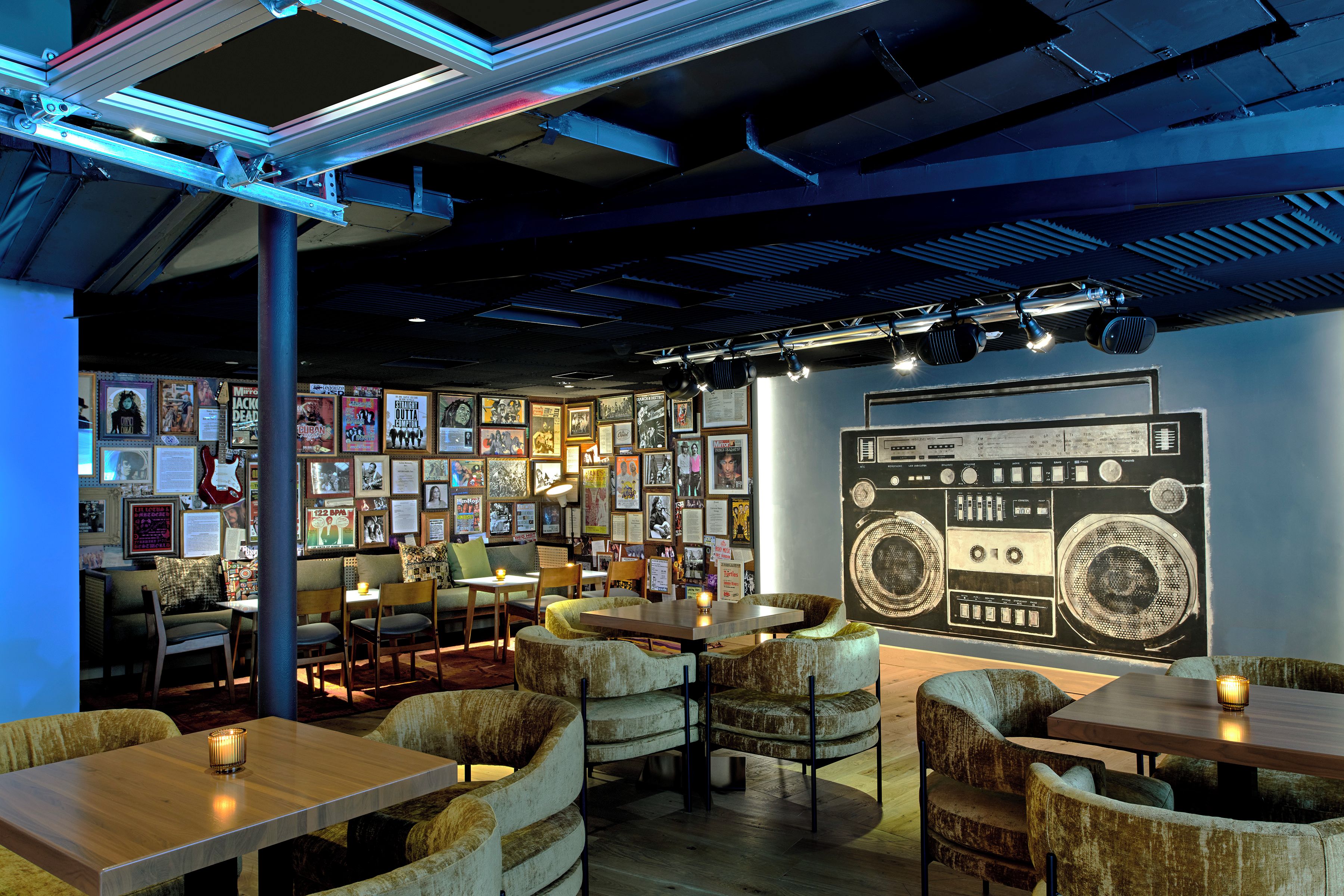 Un café acogedor con muebles de madera, una pared de cuadros enmarcados y una radio antigua.