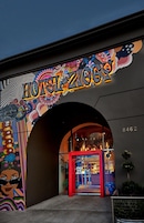 Un edificio con un mural colorido y el nombre 'HOTEL ZONES' iluminado sobre la entrada.