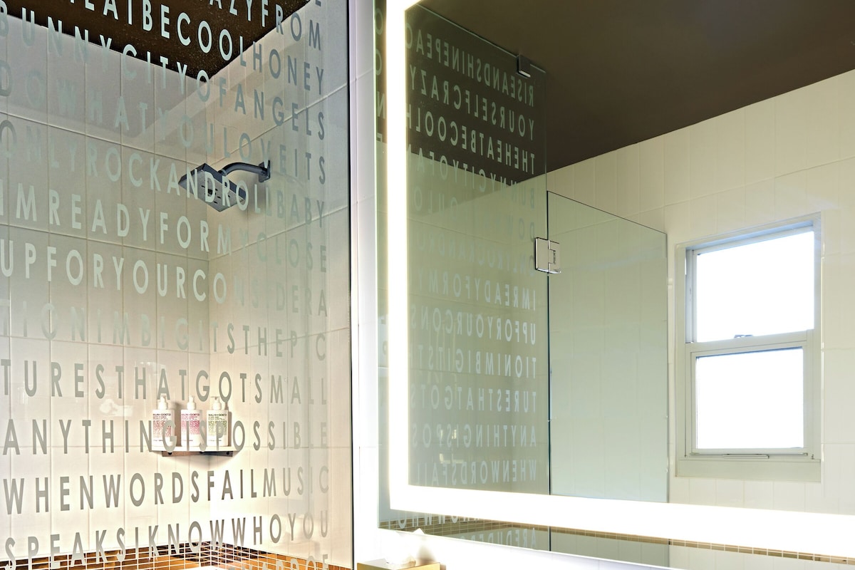 A bathroom with a large mirror, a sink, and a toilet. The walls have text and patterns.