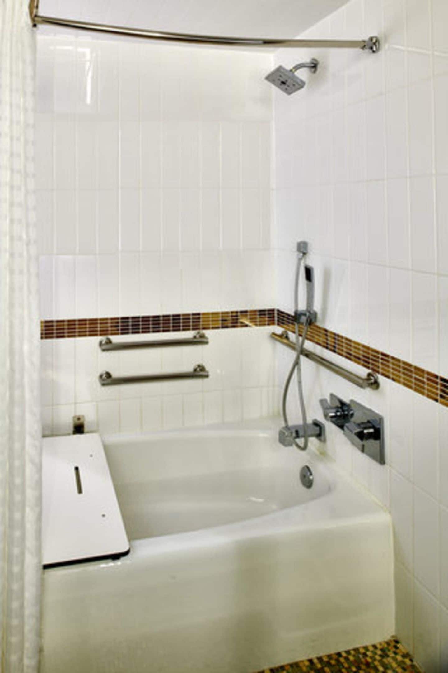Een standaard badkamer met een bad, douche en handdoekhouder.
