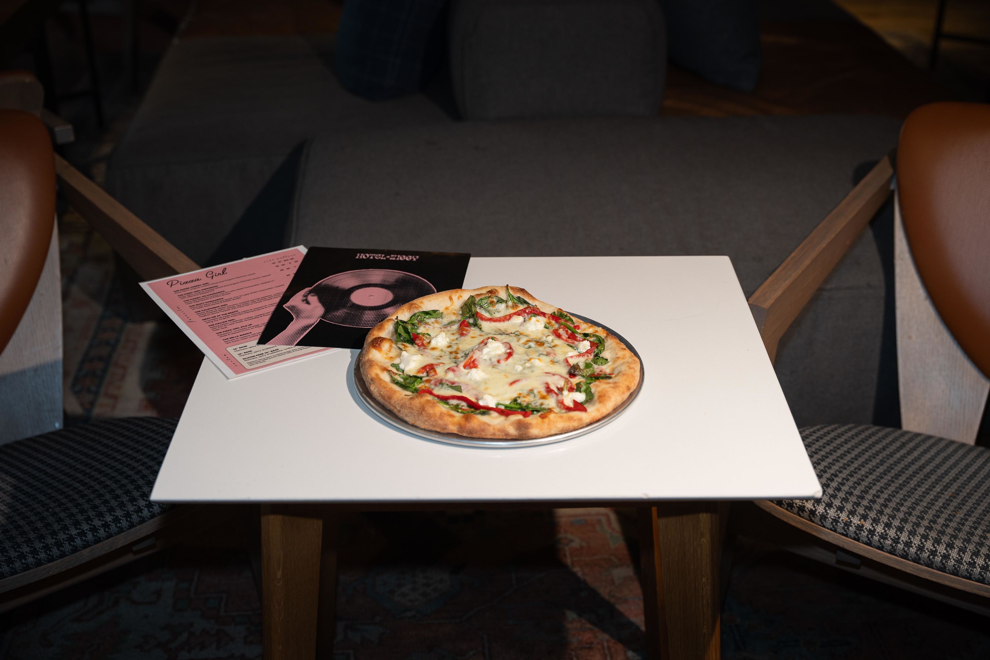 A pizza on a white table with a menu beside it.