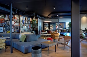 A modern lounge area with a blue sofa, wooden tables, and a variety of posters and memorabilia on the walls.