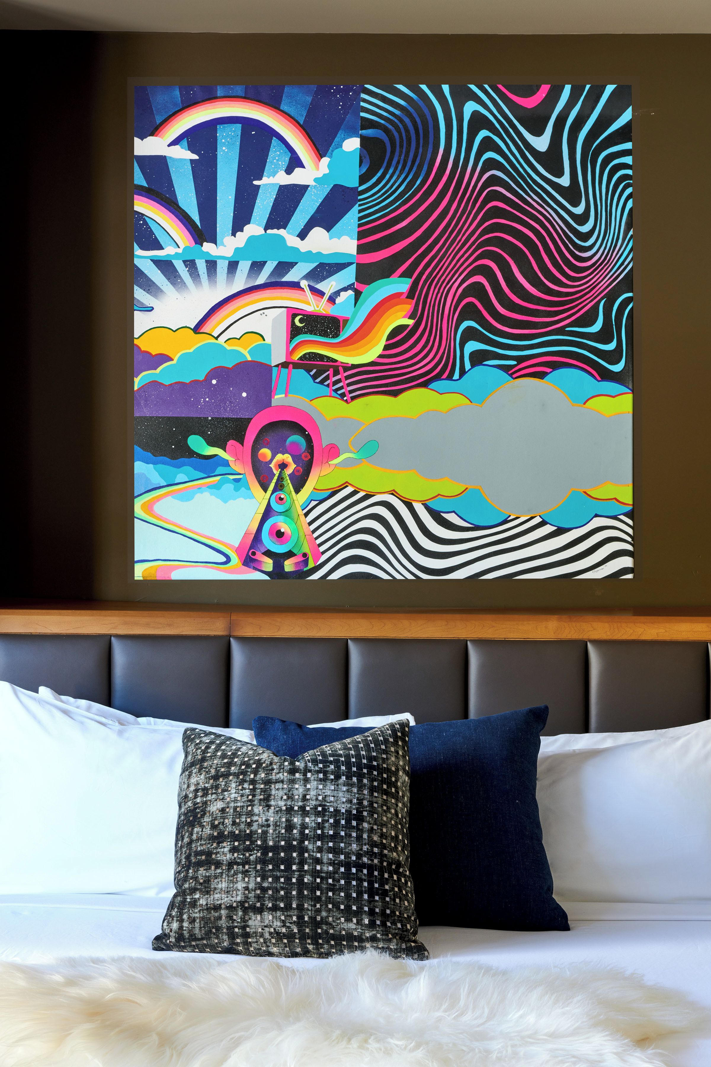 A bedroom with a bed, pillows, and a large abstract painting on the wall.