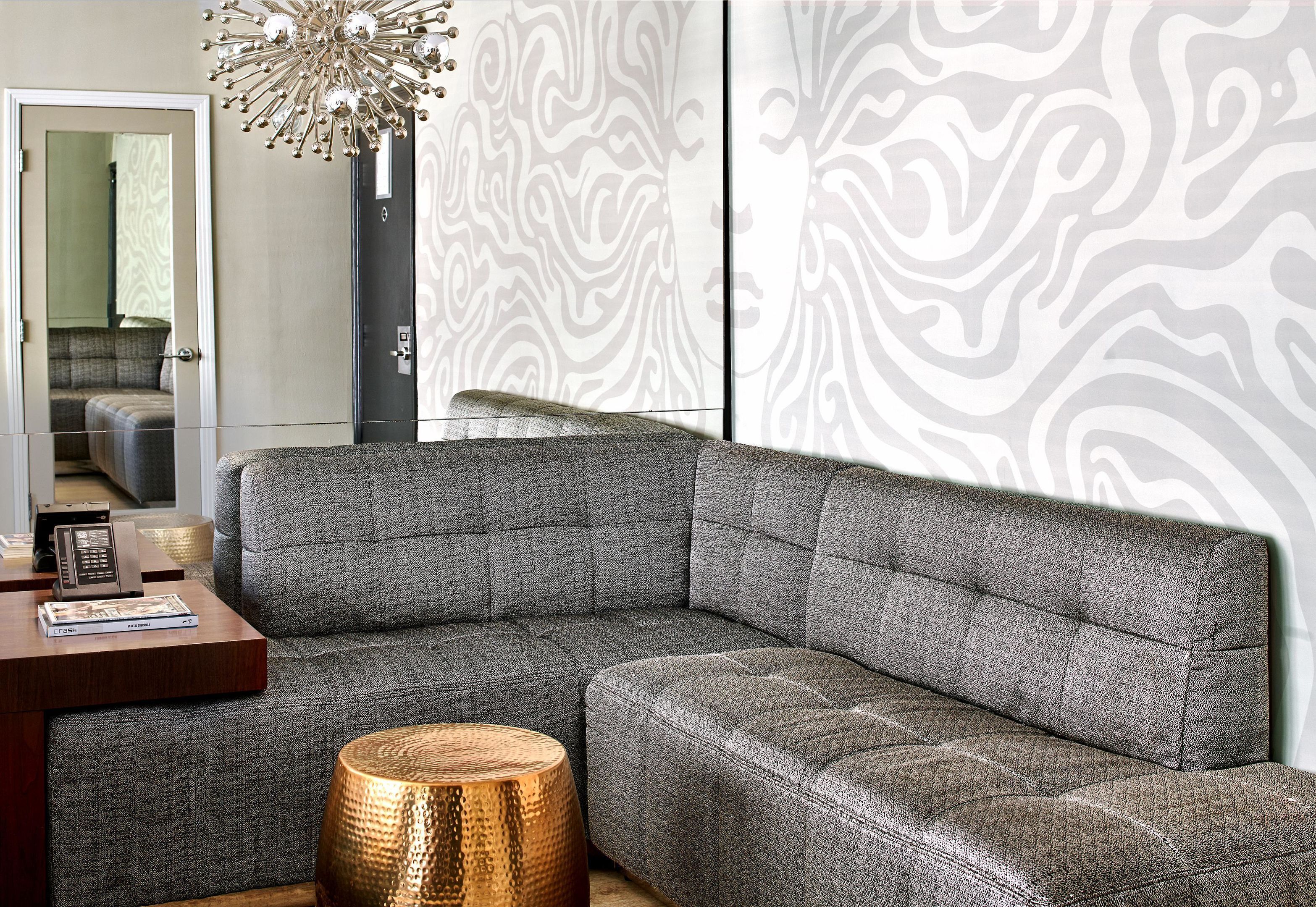 A modern living room with a sectional sofa, a wooden coffee table, a decorative floor lamp, and a patterned wall.