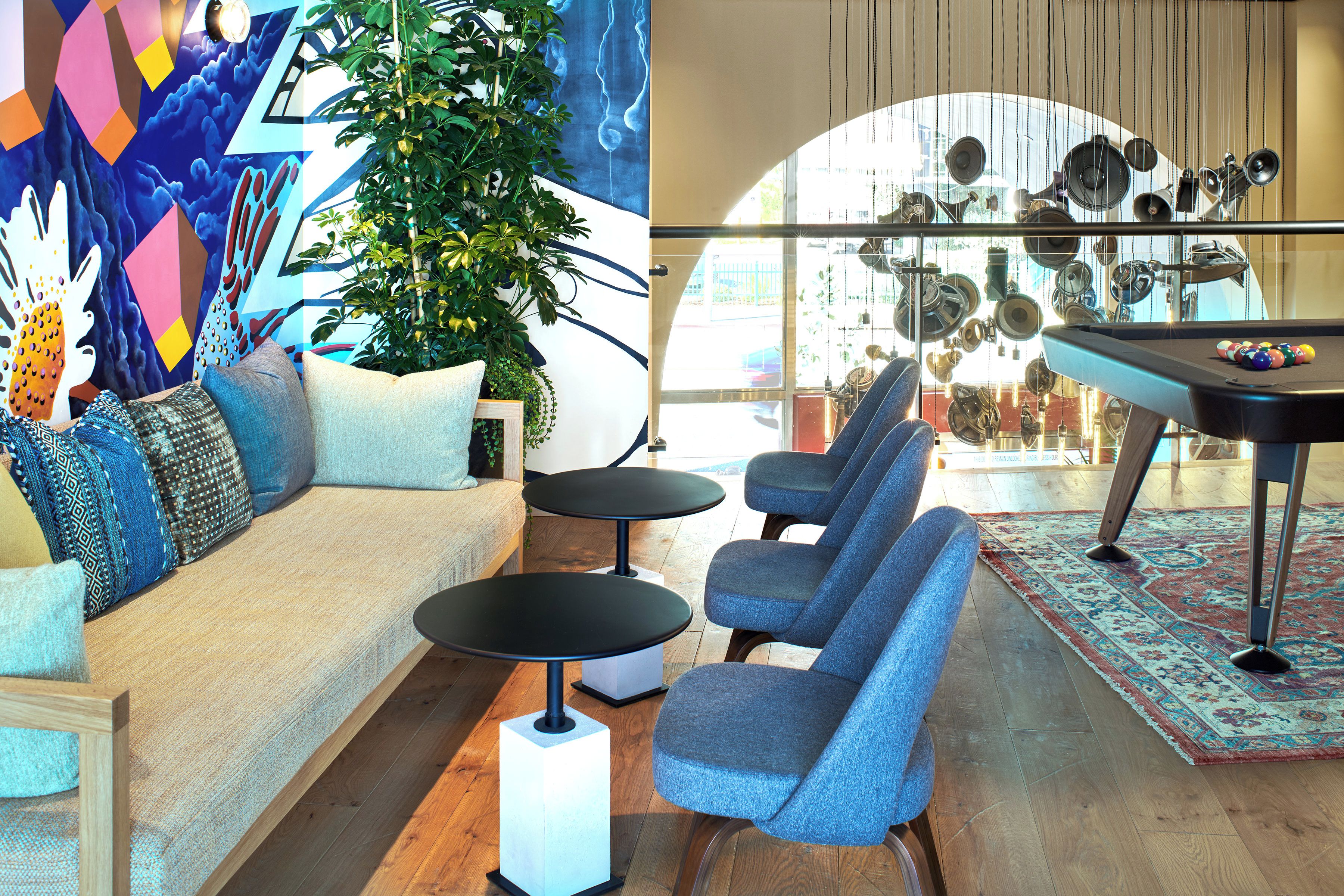 Een moderne zithoek met een bank, fauteuils, een pooltafel en een decoratieve wand.