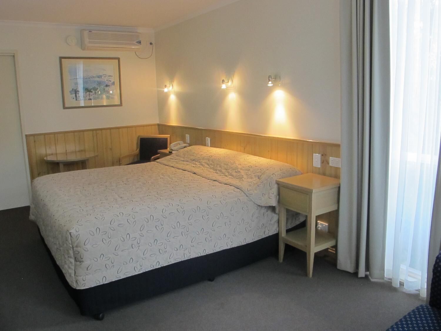 A hotel room with a large bed, bedside tables, a desk, and a chair.