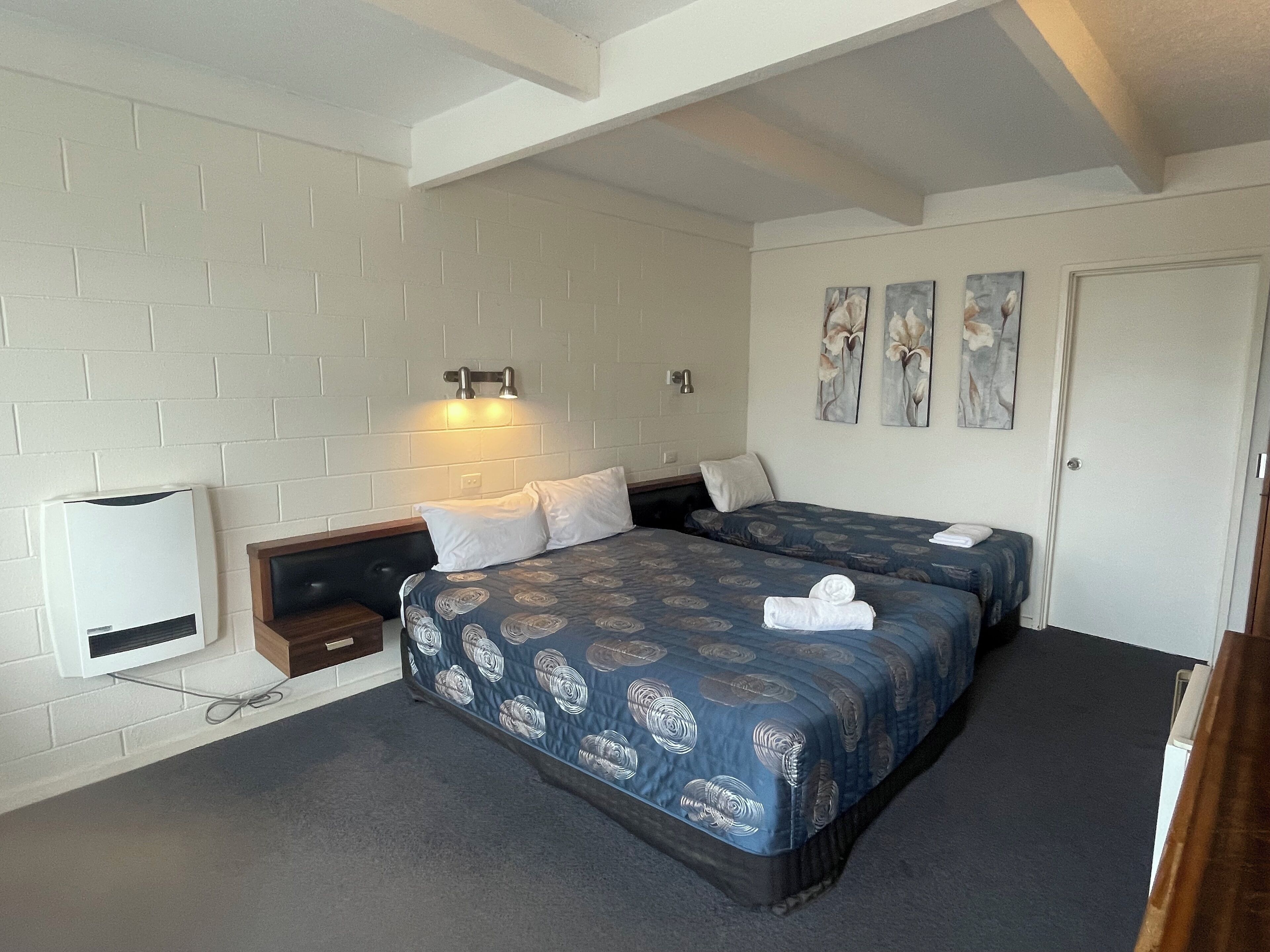 A hotel room with two beds, a white brick wall, a ceiling fan, and a door.