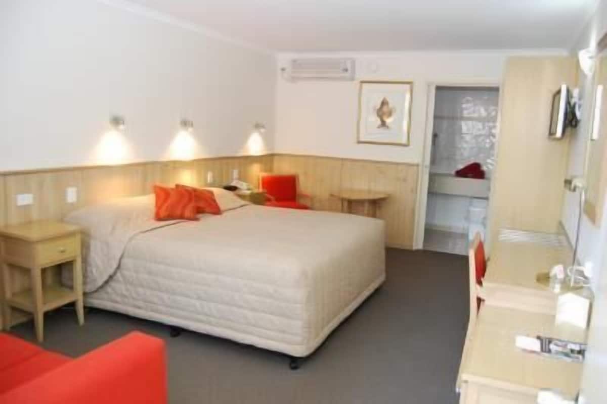 Una habitación de hotel con cama, mesita de noche, cómoda y espejo.