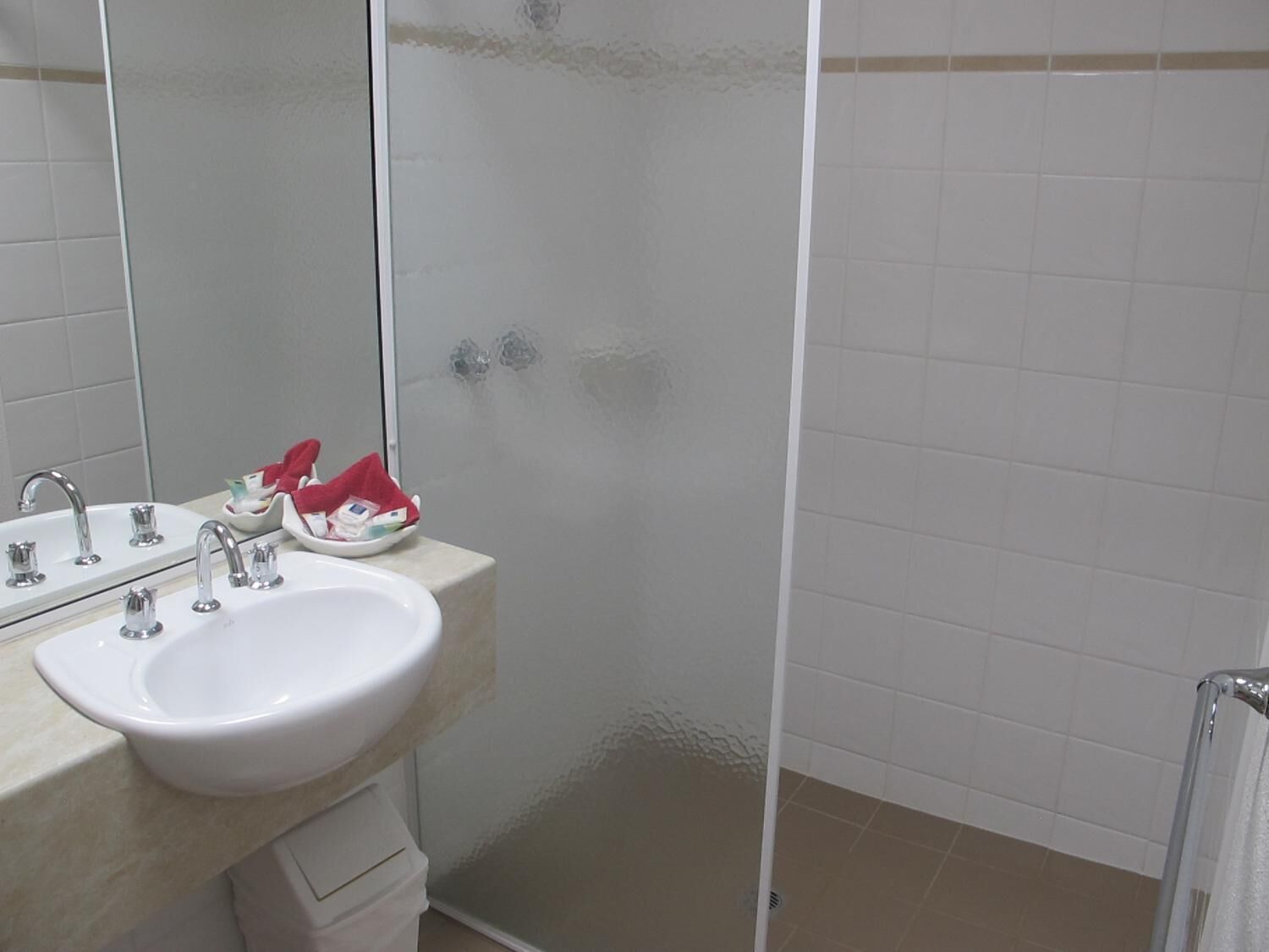 A bathroom with a white sink, mirror, and shower area.
